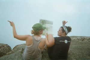 Two women point in different directions while looking at a map.